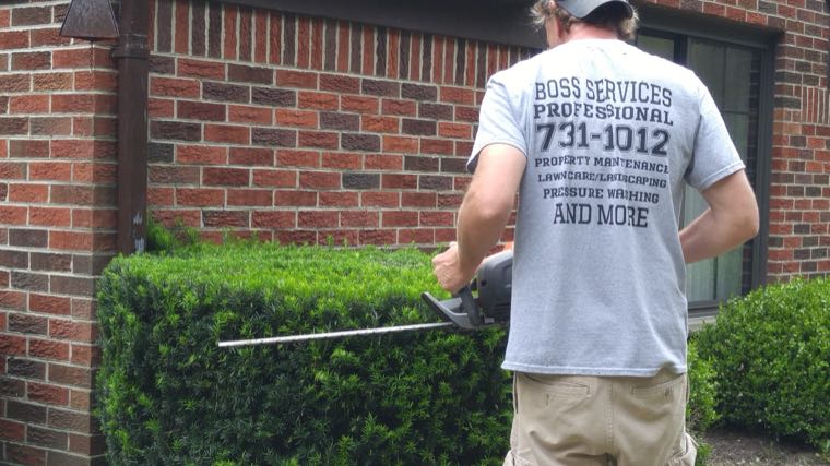 BOSS Services crew member trimming shrubs